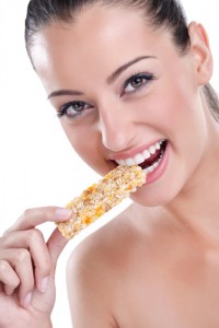 Young pretty woman eating granola bar, isolated on white background